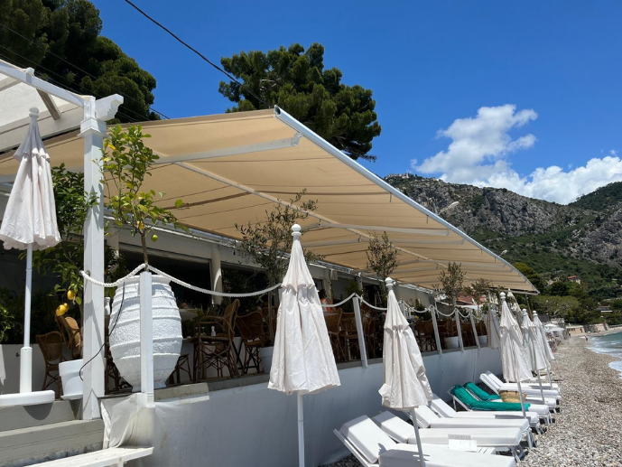 Stores banne sur-mesure installés sur la terrasse d'un restaurant de plage face à la mer